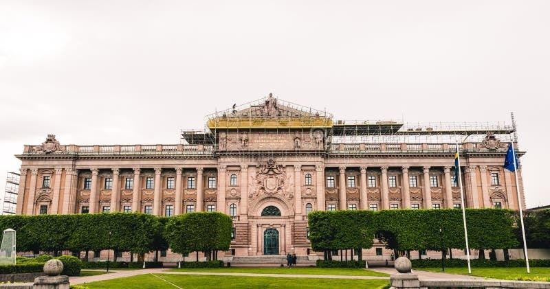Sveriges riksdagshus med svenska och blå EU-flaggor framför fasaden